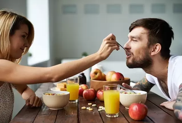 Woman feeds man nuts to increase his strength